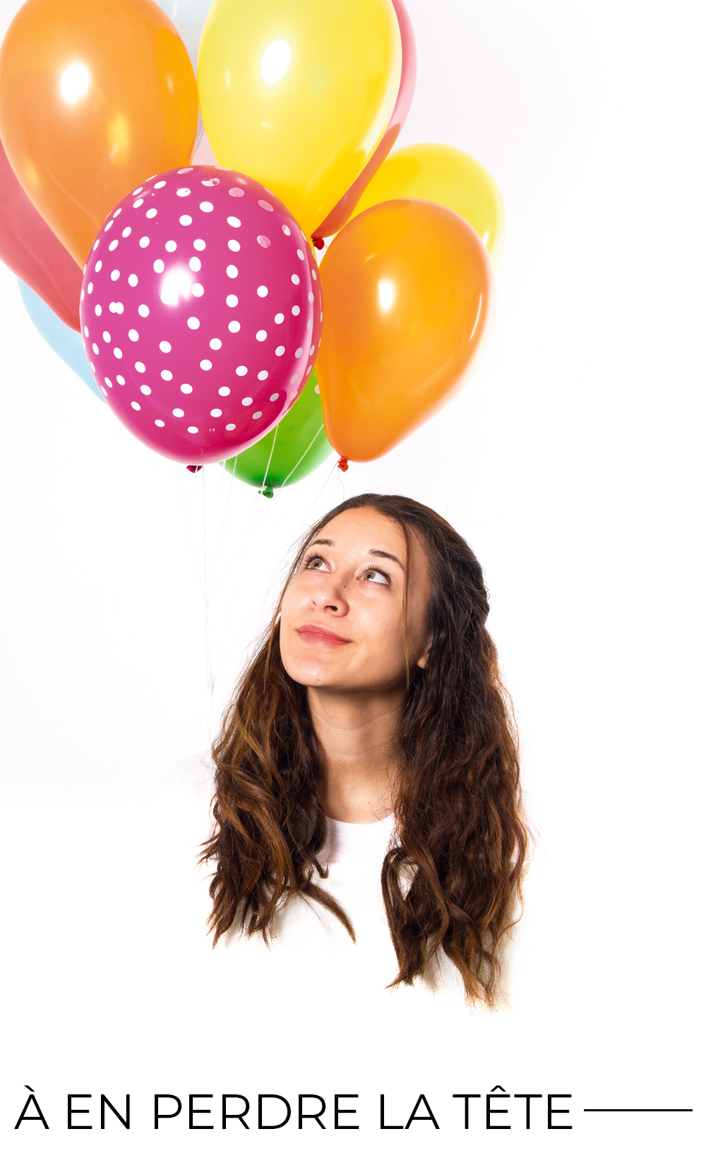 Une personne qui a une tête décapitée et qui regarde de haut, elle est brune avec des cheveux ondulés, des ballons de plusieurs couleurs sont en haut à gauche